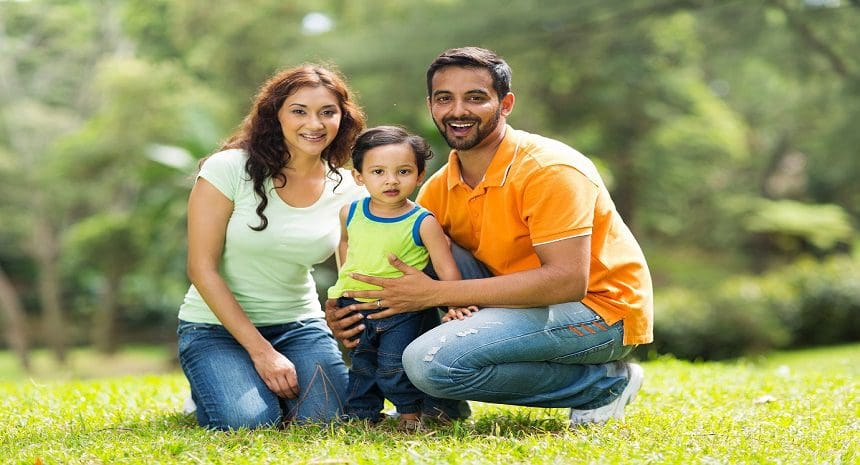 A man and woman with a child in the grass.