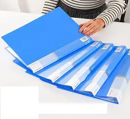 A person holding a file folder in front of a table.