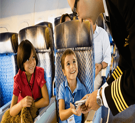 A man is handing something to two children on an airplane.