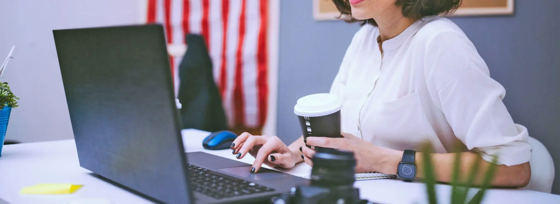 A woman is sitting at her desk with a coffee.