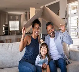 A family sitting on the couch under an open box.