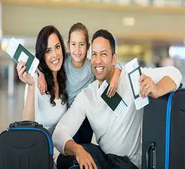 A family is sitting in an airport with their luggage.