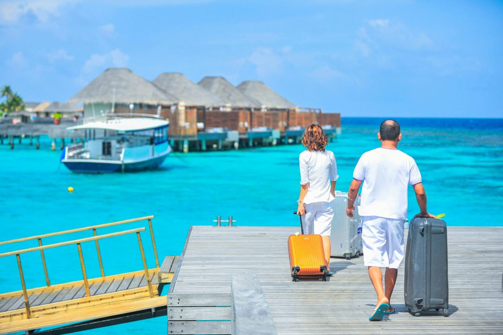 A man and woman walking on the dock with luggage.