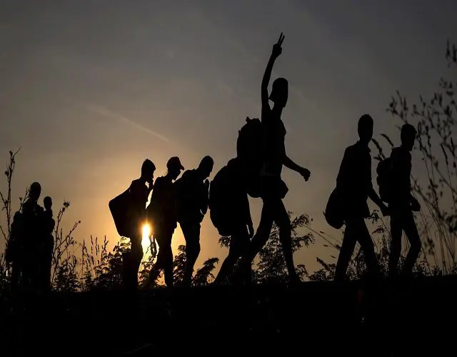 A group of people walking across the grass.